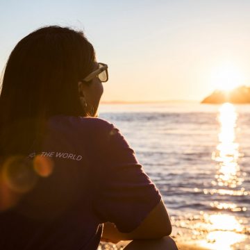 UW student sits in front of the water as the sun sets